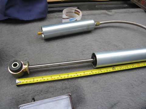 1986 Ford Bronco - A shock absorber is laid out next to a measuring tape, likely for comparison or installation purposes.