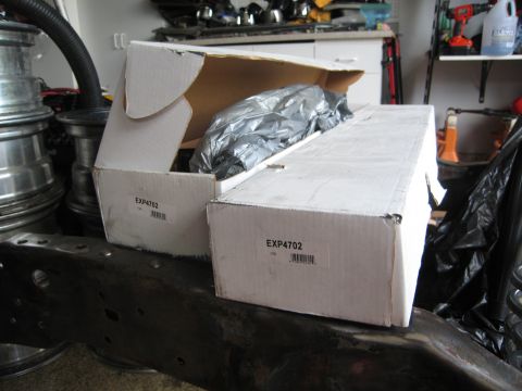1986 Ford Bronco - Two boxes of Pro Comp Shocks sit on a vehicle frame in a garage setting.