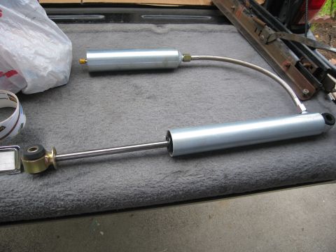 1986 Ford Bronco - Two shock absorbers are laid out on a textured surface, possibly a truck bed.