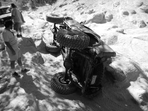 1997 Ford Ranger - A vehicle has rolled over on a challenging off-road course, with onlookers observing the scene.