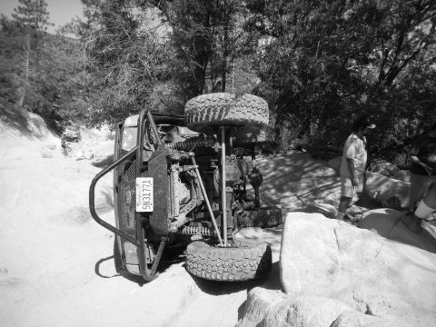 1997 Ford Ranger - This off-road vehicle has overturned on a rocky trail, with onlookers observing the scene.