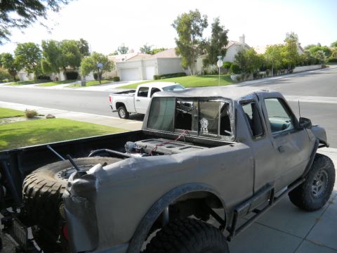 1997 Ford Ranger - A heavily modified pickup truck sits in a driveway, with a second white pickup truck visible on the street.