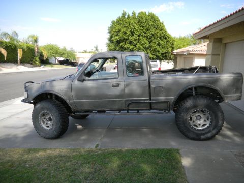 1997 Ford Ranger - Side view of a modified 1997 Ford Ranger pickup truck with oversized wheels and a matte gray finish.