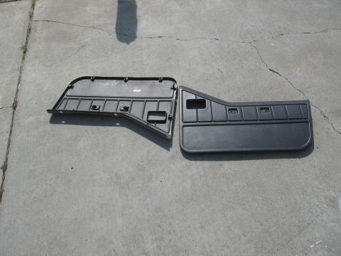 1986 Ford Bronco - Two black plastic door panels are laid out on a concrete surface.