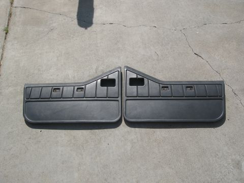 1986 Ford Bronco - A pair of dark gray plastic door panels, likely for a Jeep YJ, are displayed on a concrete surface.