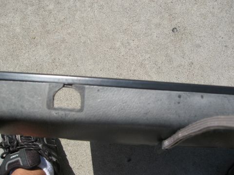 1986 Ford Bronco - Interior door panel part with a cutout and a strap. A shoe is visible in the foreground.