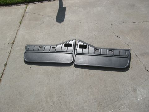 1986 Ford Bronco - Pair of dark gray plastic car door panels with speaker grilles shown on concrete.