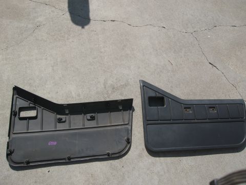 1986 Ford Bronco - Two black interior door panels are shown laid out on a cracked concrete surface.
