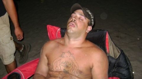 2005 Ford Excursion - A man is asleep in a camping chair on what appears to be a sandy area at night.