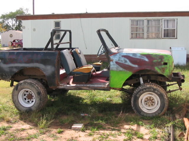 Project vehicle with roll cage, missing doors and hood paint primer. Off-road tires visible