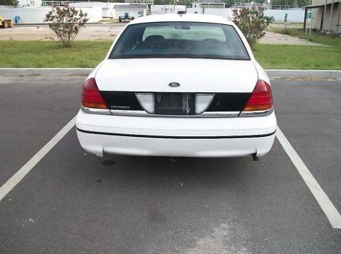 1999 Ford Crown Victoria - Rear view of a white sedan parked in a lot, showing its taillights and black trim panel.