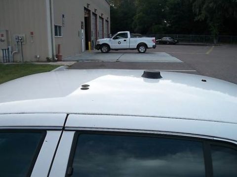 1999 Ford Crown Victoria - The foreground shows the roof of a white sedan, with a white pickup truck visible in the background.