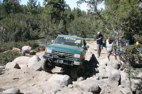 1991 Ford Bronco - 1991 Ford Bronco tackling a challenging off-road course with large boulders.