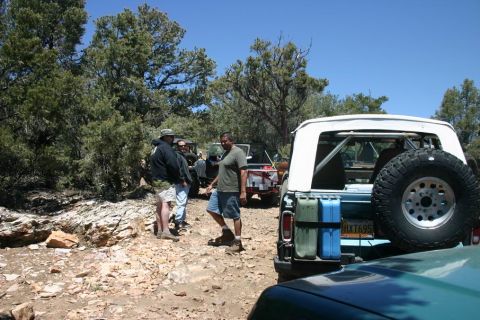 1991 Ford Bronco - A group of off-road enthusiasts gather with their vehicles on a rocky trail under a clear blue sky.