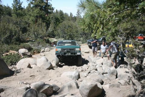 1991 Ford Bronco - 1991 Ford Bronco tackling a challenging rocky trail in a wooded area.
