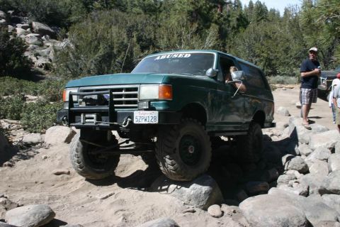 1991 Ford Bronco - Green 1991 Ford Bronco tackling a challenging off-road course with large rocks.