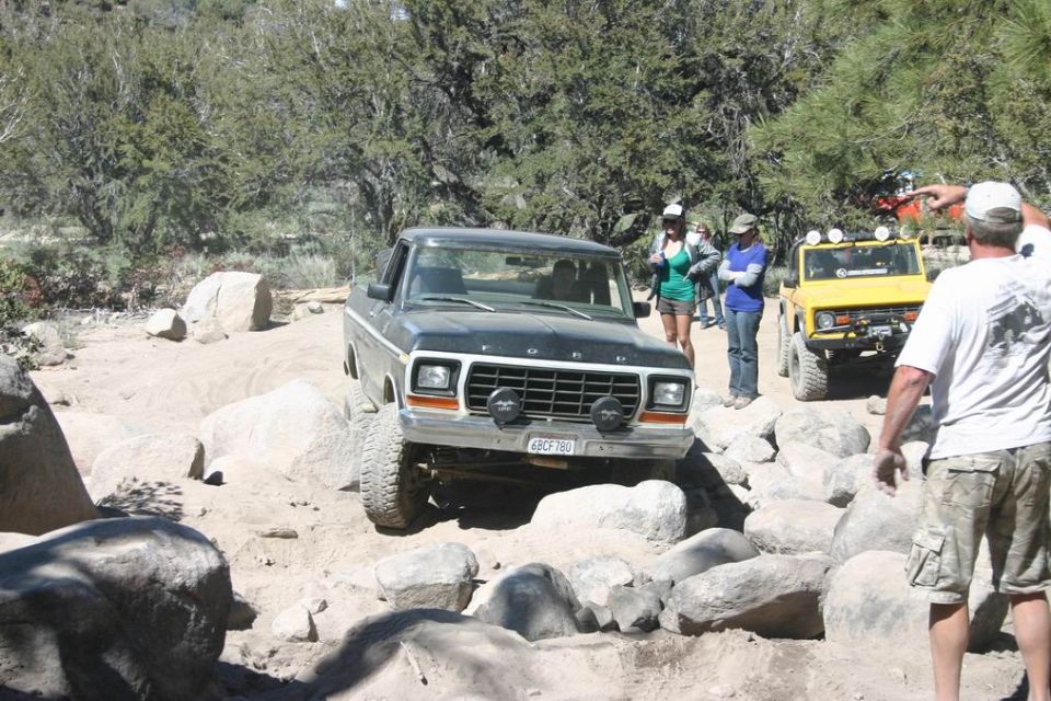 Dark green Ford F-Series truck navigating a rocky trail, front view
