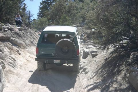 1991 Ford Bronco - A green 1991 Ford Bronco navigates a challenging rocky trail, its off-road capabilities.