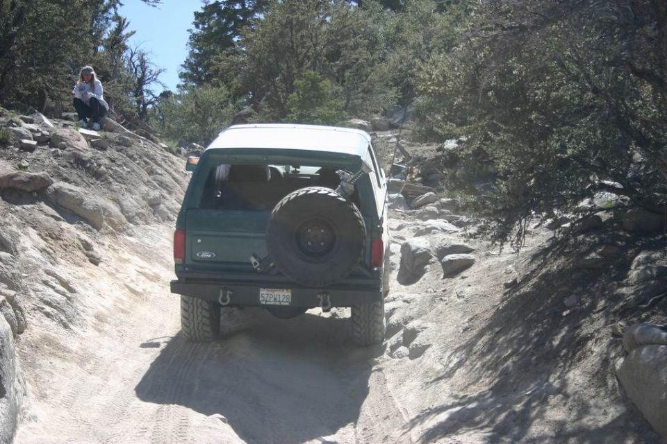 Green 1991 Ford Bronco on a rocky trail, rear view