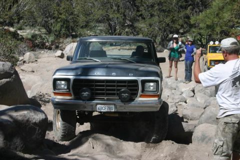 1991 Ford Bronco - Ford Bronco off-roading with a yellow Jeep visible in the distance.
