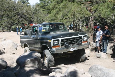 1991 Ford Bronco - This Ford Bronco is navigating a rocky trail with trees and people in the background.