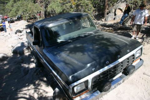 1991 Ford Bronco - This Ford F-Series truck navigates a challenging rocky trail, with other vehicles visible in the background.