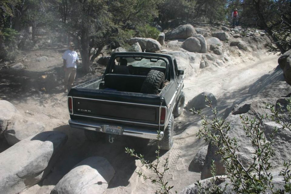 1978 Ford Bronco with spare tire in the bed, navigating a rocky off-road trail. License plate reads 6RCF780