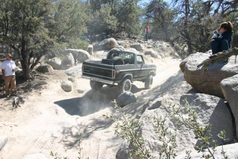 1991 Ford Bronco - A classic Ford Bronco navigates a challenging off-road course with spectators watching from the side.