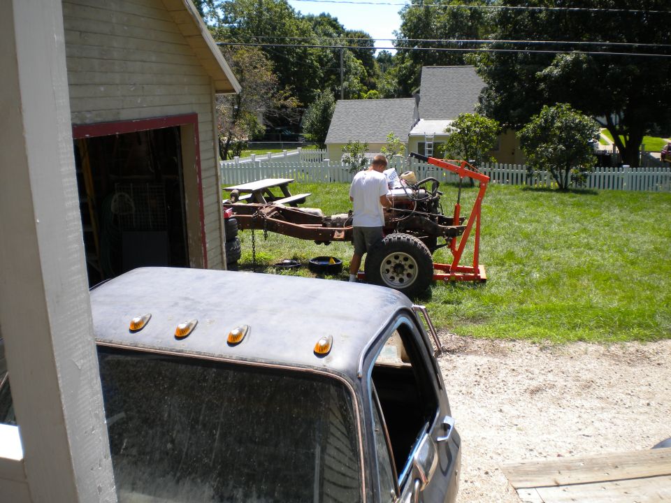 Truck chassis with engine hoist and a partial view of a dark pickup truck cab