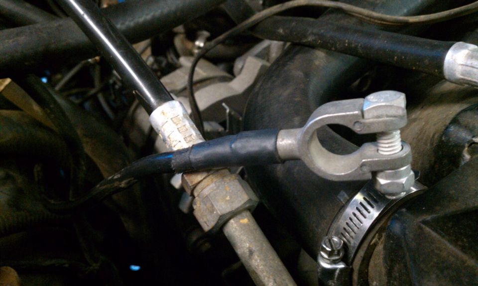 Battery terminal clamp on a black hose with a metal clamp and hose clamp