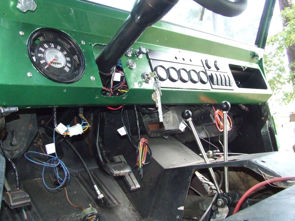 Green 1976 Ford Bronco dashboard with exposed wiring, two gear shifters, and a speedometer