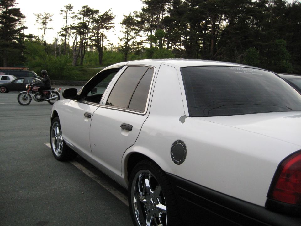 White Ford Crown Victoria sedan side view with chrome wheels in parking lot