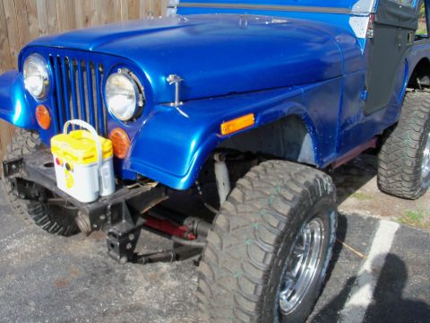 1978 Jeep CJ5 - A blue Jeep CJ5 is parked, showing its front end and large off-road tires.