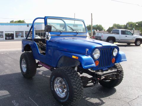 1978 Jeep CJ5 - A blue Jeep CJ5 with a roll cage and lifted suspension is parked on asphalt.