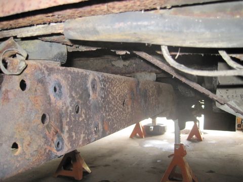 1979 Ford Bronco - Heavily rusted vehicle frame and suspension parts are visible, supported by jack stands.