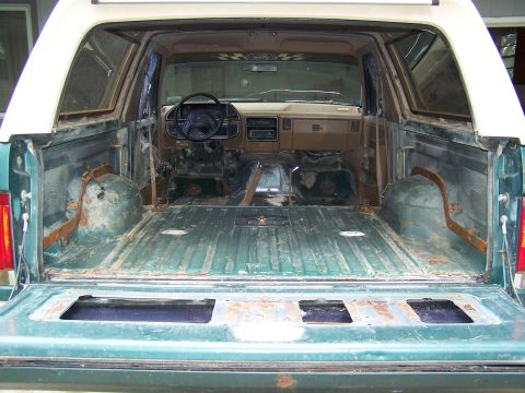 1989 Ford Bronco - The interior and cargo area of a 1989 Ford Bronco are visible, showing a stripped-down condition.