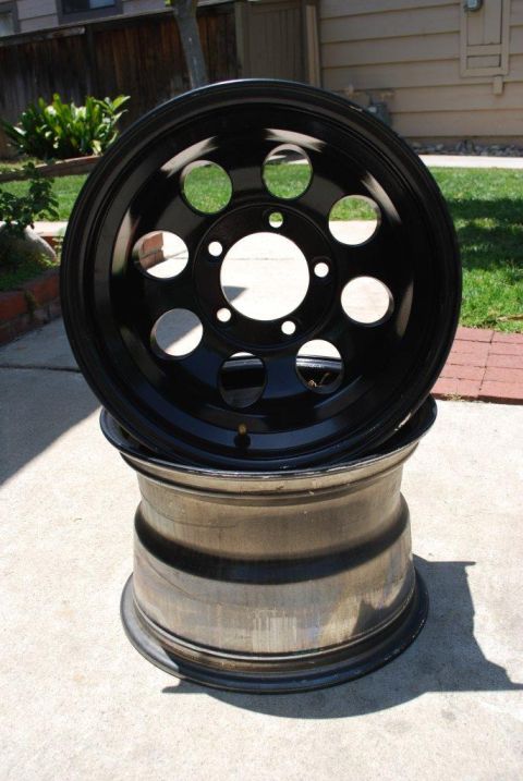 1996 Ford Bronco - Two black rims are shown outdoors. The top rim has multiple circular holes.