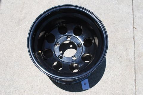 1996 Ford Bronco - A single black steel wheel with a multi-hole design is shown against a concrete surface.