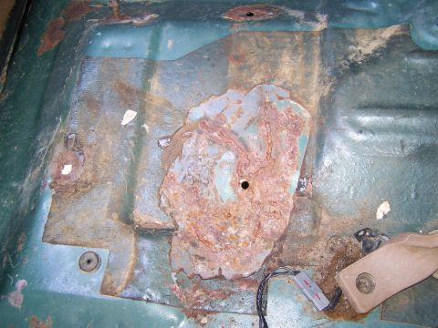 1989 Ford Bronco - The interior floor pan shows significant rust damage and exposed metal.