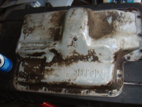 Ford oil pan with "Metric" stamped on it, covered in oil residue