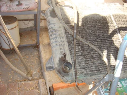 Radiator assembly with hoses and mounting bracket. Bag of concrete mix on shelf above