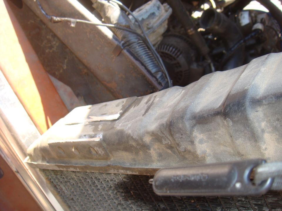 Close-up of a vehicle's radiator and engine bay components, with 'SUPERMOTORS' text visible