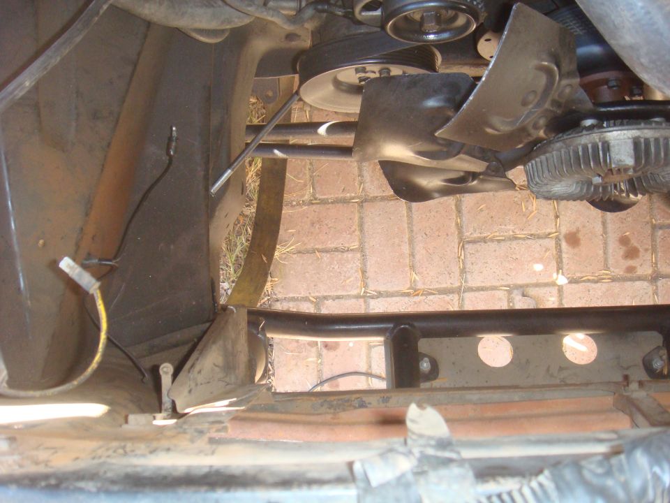 Close-up of engine fan, belts, and pulleys. Some metal bracing is visible