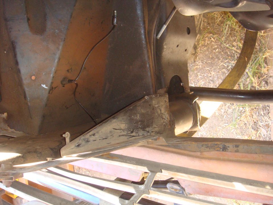 Undercarriage of a vehicle showing rusted metal frame components and a black wire with a connector