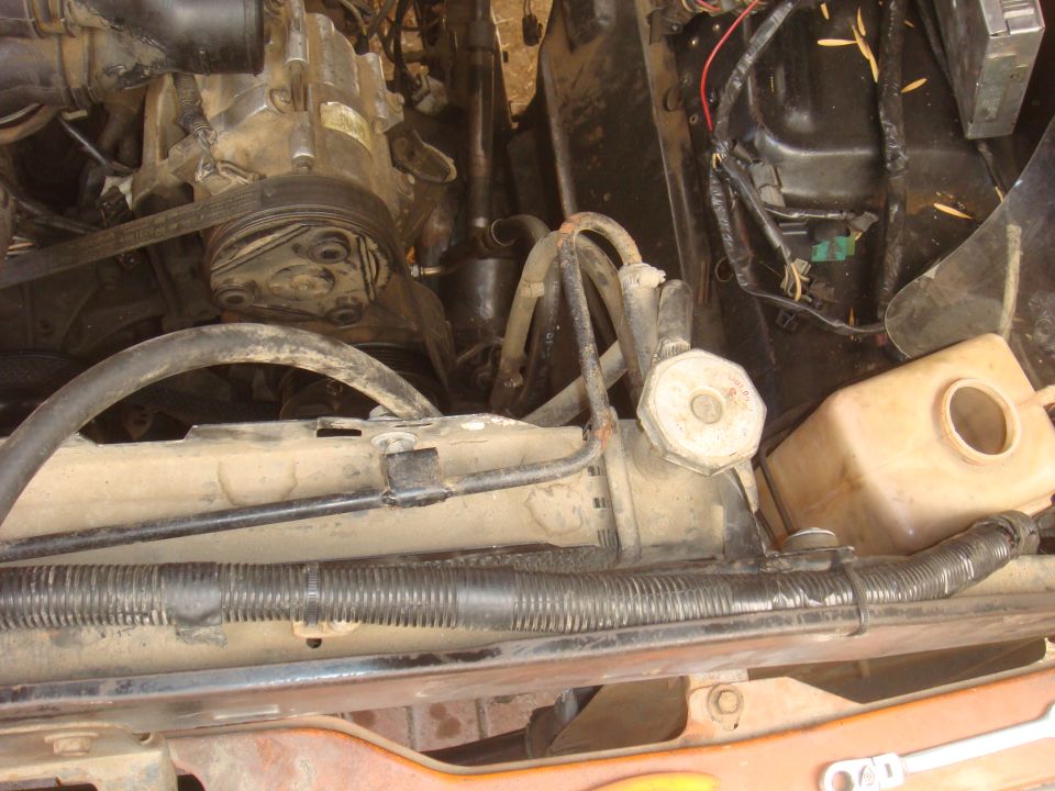 engine bay with AC compressor, hoses, and radiator visible