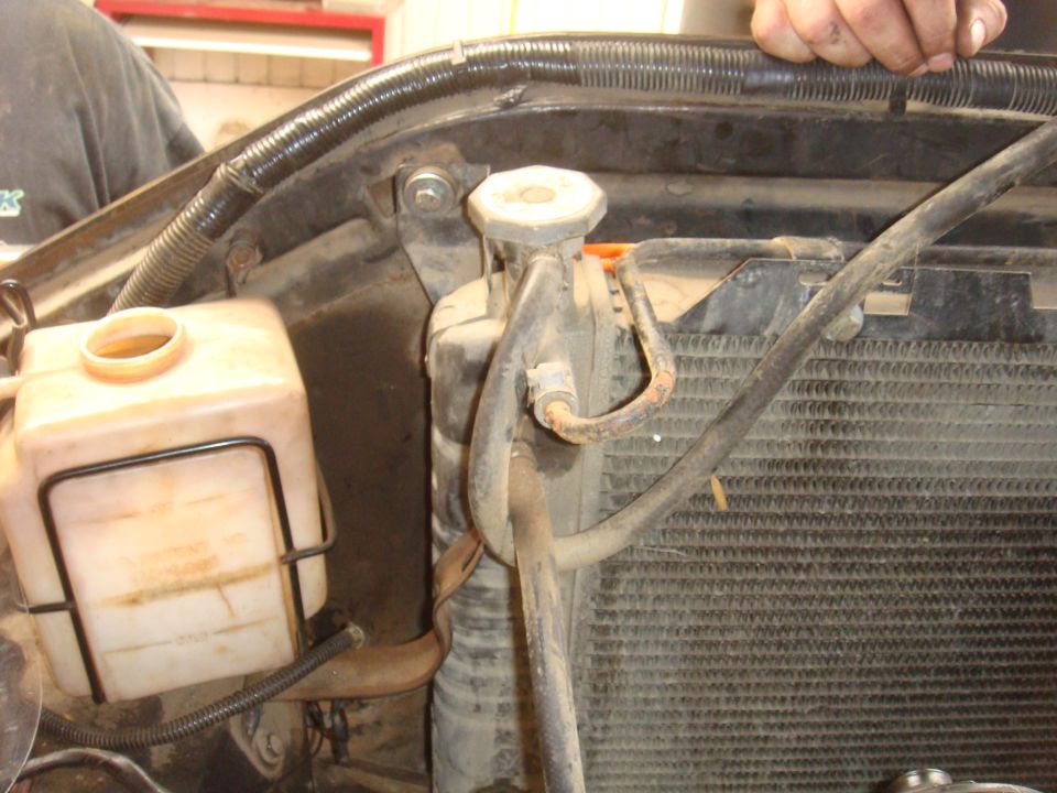 Engine bay view of radiator, coolant overflow tank, and hoses