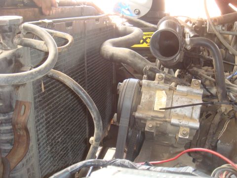 Engine bay showing radiator, hoses, and AC compressor