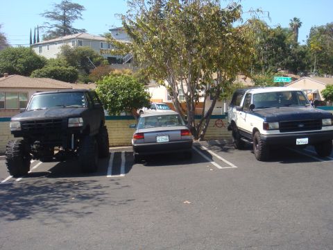 Lifted black 1992 Ford Bronco parked next to a white and blue Bronco