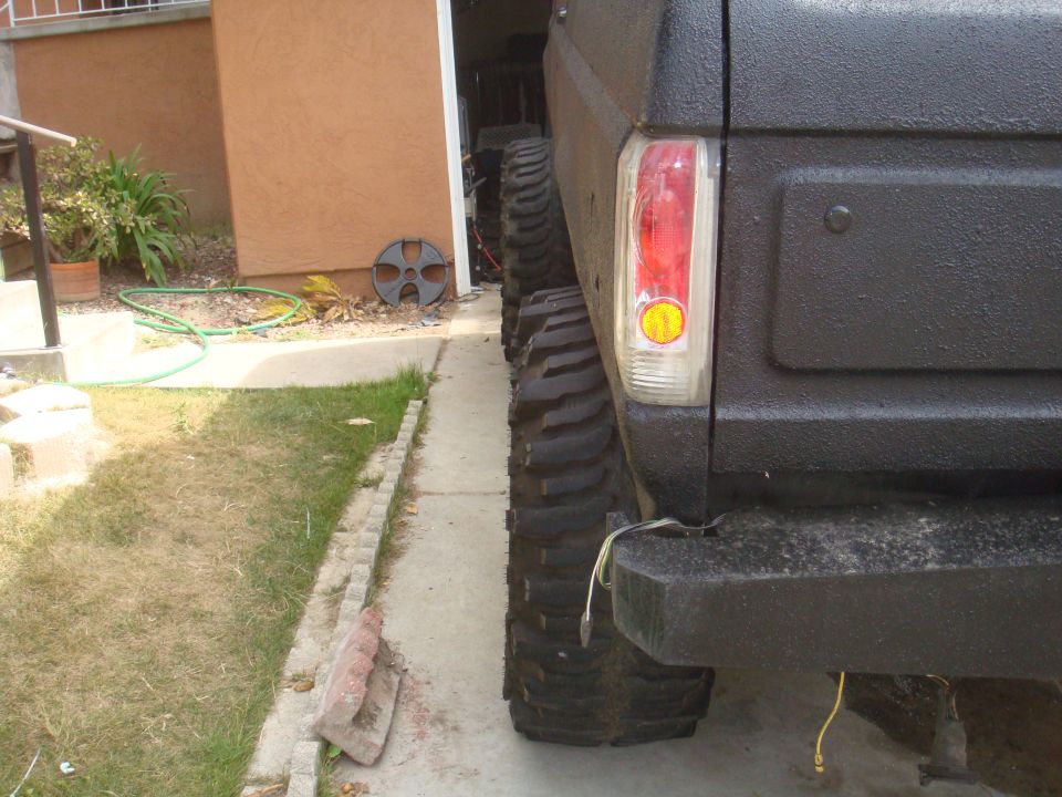 Black Ford Bronco rear quarter panel with large off-road tires and a visible taillight