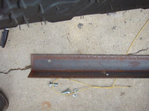 Tire tread above a rusty metal bracket with bolts and nuts on concrete
